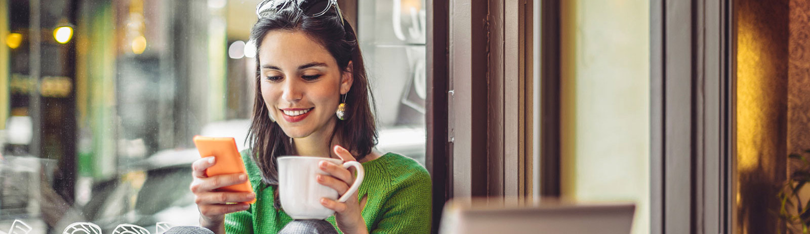 Woman using cell phone in coffee shop