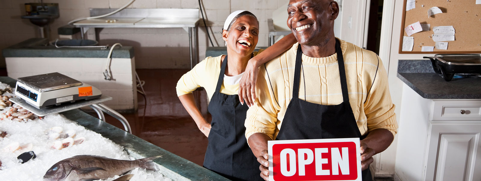Husband and wife business owners in store with open sign